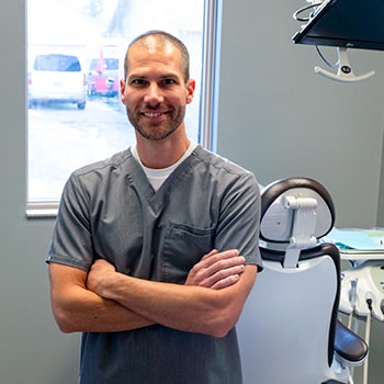 Dr. Ryan Bakke smiling while folding his arms