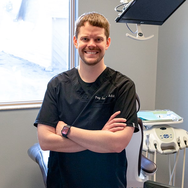 Dr. Troy Larsen smiling inside the dental office in his dentist uniform
