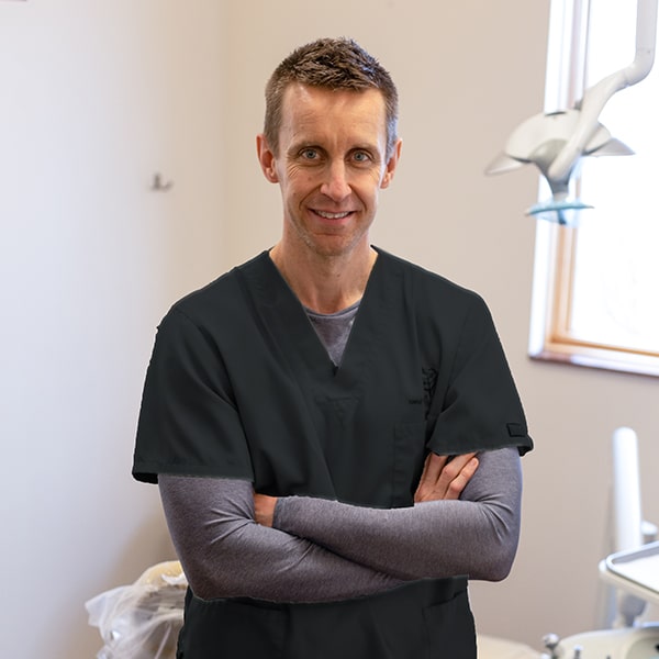 Dr. Nick Shawd smiling inside the dental office with his arms folded