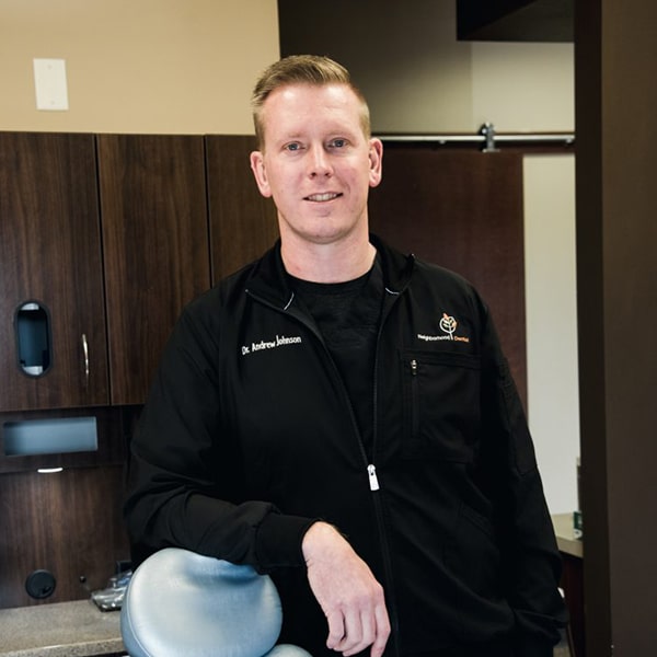 Dr. Andy Johnson smiling inside the dental office in his dentist uniform