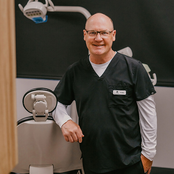 Dr. Robert Swenson smiling leaning on a dental chair
