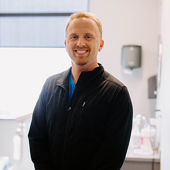 Dr. Sean Rasmusson smiling while leaning on a dental chair